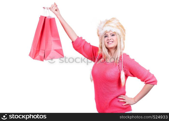 Clothing, seasonal sales and accessories concept. Woman in warm furry winter hat holding shopping bags. Woman in furry winter hat holding shopping bags