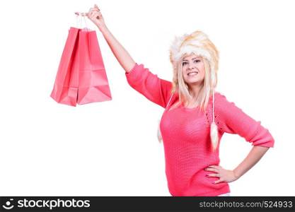 Clothing, seasonal sales and accessories concept. Woman in warm furry winter hat holding shopping bags. Woman in furry winter hat holding shopping bags
