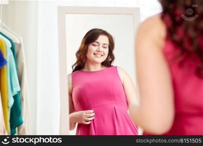 clothing, wardrobe, fashion, style and people concept - happy plus size woman posing at mirror at home