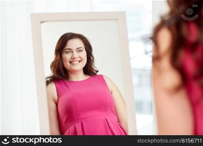 clothing, wardrobe, fashion, style and people concept - happy plus size woman posing at mirror at home