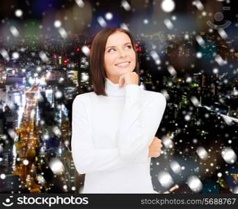 clothing, winter holidays, christmas and people concept - smiling young woman iin white sweater over snowy night city background