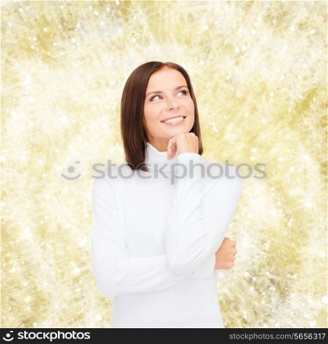 clothing, winter holidays, christmas and people concept - smiling young woman in white sweater over yellow lights background