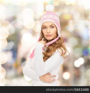 clothing, winter holidays, christmas and people concept - smiling young woman in hat and sweater over lights background