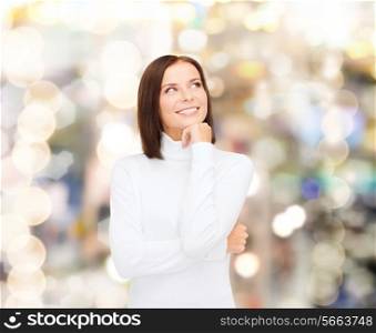 clothing, winter holidays, christmas and people concept - smiling young woman in white sweater over lights background