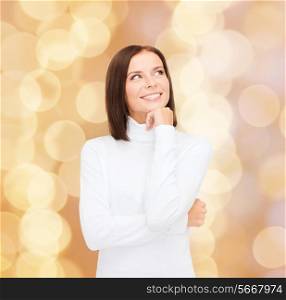 clothing, winter holidays, christmas and people concept - smiling young woman in white sweater over beige lights background