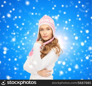 clothing, winter holidays, christmas and people concept - smiling young woman in hat and sweater over blue lights background