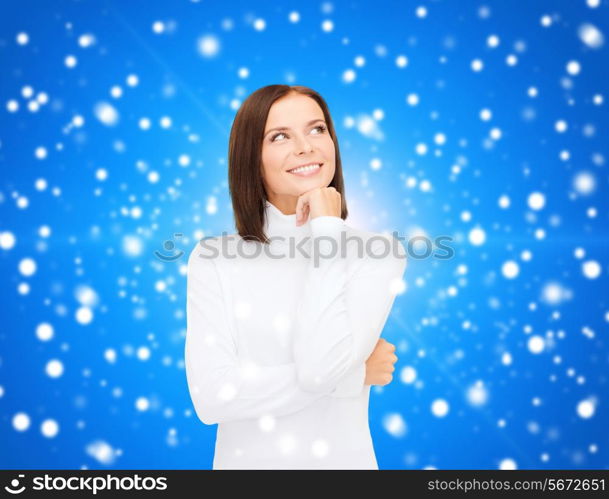 clothing, winter holidays, christmas and people concept - smiling young woman in white sweater over blue snowing background