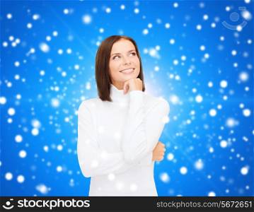 clothing, winter holidays, christmas and people concept - smiling young woman in white sweater over blue snowing background