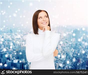 clothing, winter holidays, christmas and people concept - smiling young woman in white sweater over snowy city background