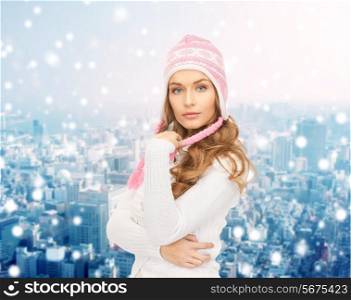 clothing, winter holidays, christmas and people concept - smiling young woman in hat and sweater over blue lights background