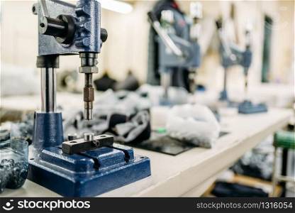 Clothing workshop, riverting machine on fabric, closeup. Dressmaking industry. Equipment on dress factory, professional tailoring