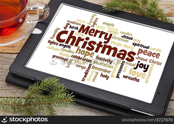 cloud of words or tags related to Christmas on a digital tablet with a cup of tea