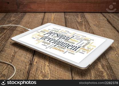 cloud of words or tags related to personal development on a digital tablet against rustic wood background