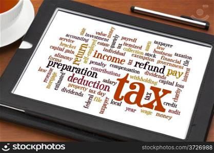 cloud of words related to taxes, preparation, paying, income, refunds, on a digital tablet with a cup of tea