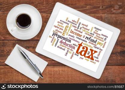 cloud of words related to taxes, preparation, paying, income, refunds on a digital tablet with a cup of coffee