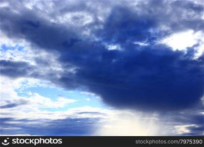 cloud with unusual shape and sunny beams. dark cloud on the light sky and sunny beams