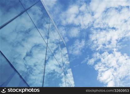 Clouds and blue sky reflection in glass skyscraper. Reflection
