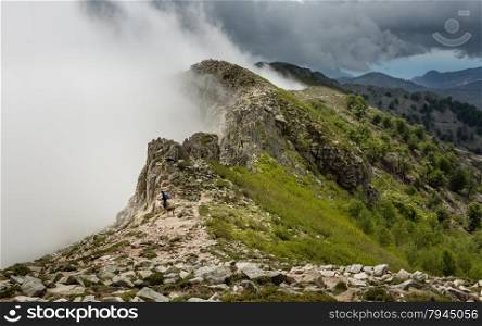 Clouds and mist meet the top of a mountain ridge on the GR20 track near Lac de Nino in Corsica