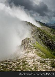 Clouds and mist meet the top of a mountain ridge on the GR20 track near Lac de Nino in Corsica