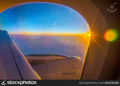 Clouds and sky as seen through window of an aircraft at sunrise