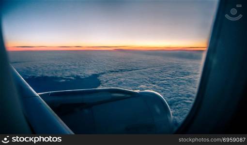 Clouds and sky as seen through window of an aircraft at sunrise