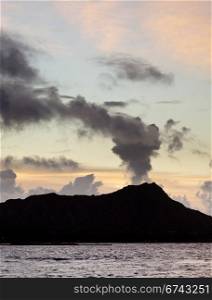 Clouds appear to be smoke from volcano of Diamond Head at sunrise in Hawaii