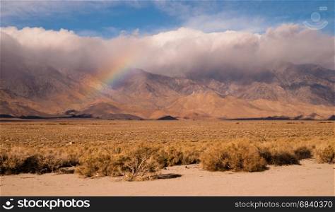 Clouds hug the Sieera Nevada Range tight as a rainbow forms in the mist