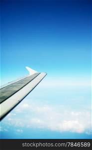 clouds in a blue sky and plane wing, view from airplane
