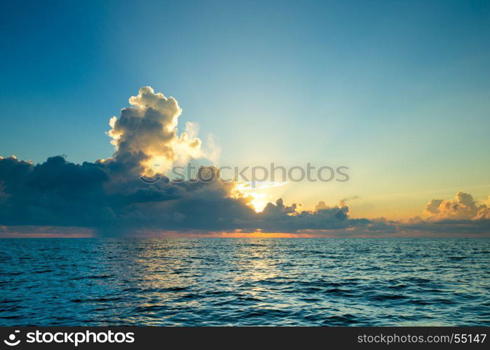 clouds on blue sky over calm sea with sunlight reflection