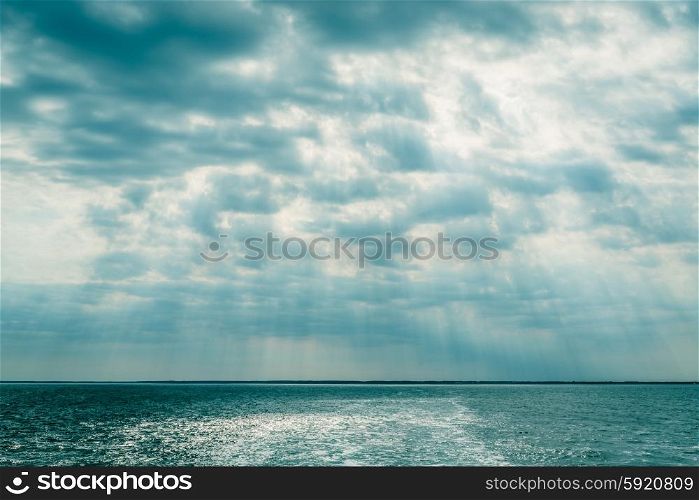 Clouds over the ocean with sunbeams in daylight