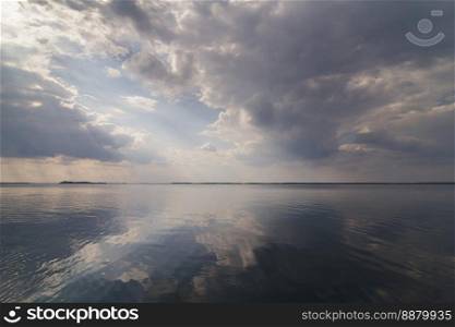 Clouds reflecting on water surface landscape photo. Beautiful nature scenery photography with skyline on background. Idyllic scene. High quality picture for wallpaper, travel blog, magazine, article. Clouds reflecting on water surface landscape photo