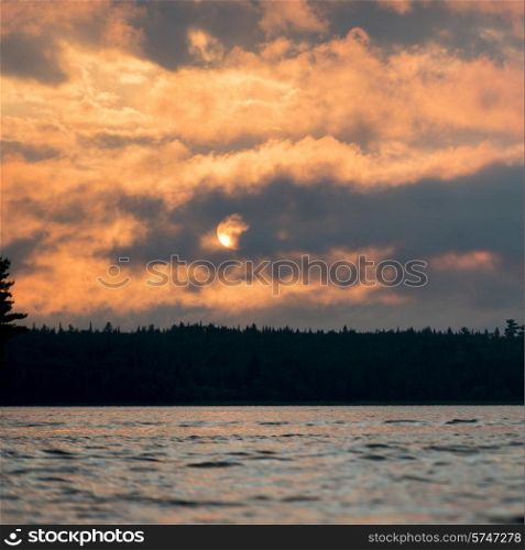 Clouds with sunglow over a lake at dusk, Lake of The Woods, Ontario, Canada