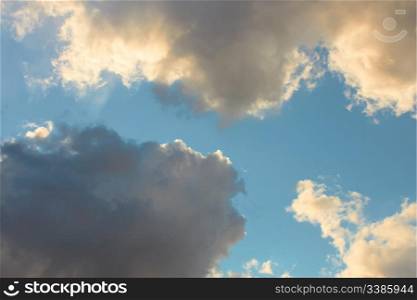 Cloudscape, dark gray and light yellowish clouds on the blue sky