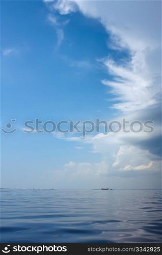 Cloudscape over the sea near the coast. Big ship sailing on the horizon