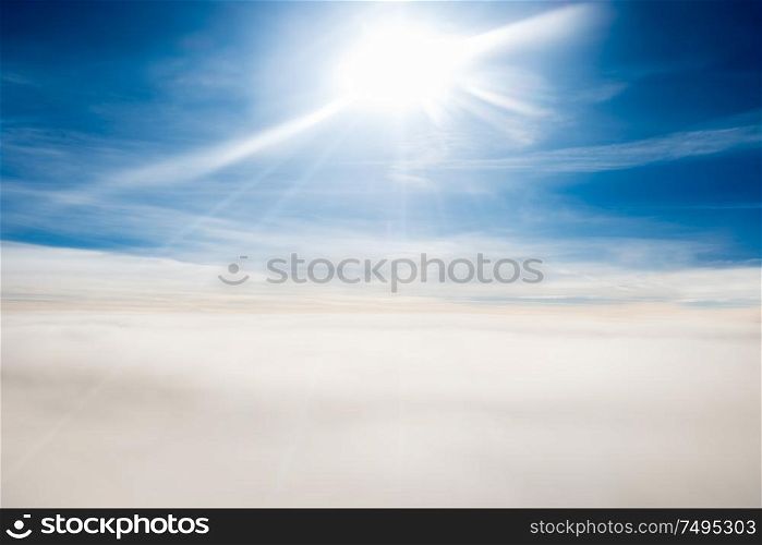 Cloudscape view with horizon line, bright sun and airplane wing