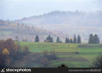 Cloudy and foggy autumn mountains scene. Peaceful picturesque traveling, seasonal, nature and countryside beauty concept scene. Carpathian Mountains, Ukraine.