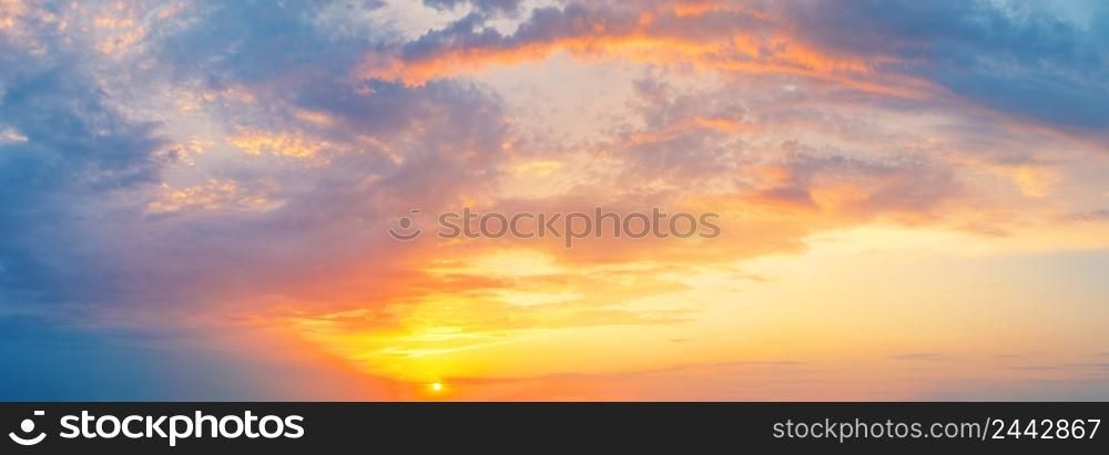 Cloudy dramatic sky with orange sun at sunset or dawn. Panorama. Cloudy dramatic sky with orange sun at sunset or dawn
