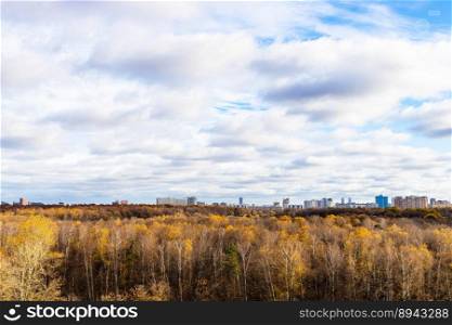 cloudy sky over forest and city on horizon on sunny autumn day