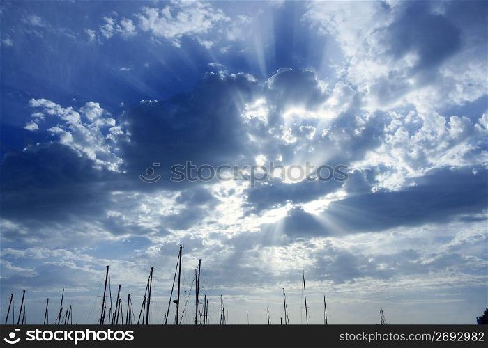 Cloudy sunset beam sky with marina sailboat masts on bottom