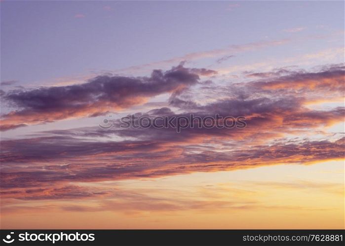 Cloudy sunset in orange and violet colors in the late summer afternoon