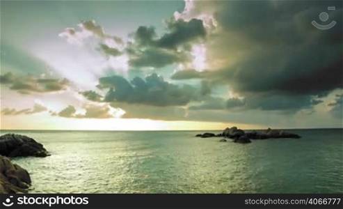 Cloudy sunset on sea with stones in water time lapse