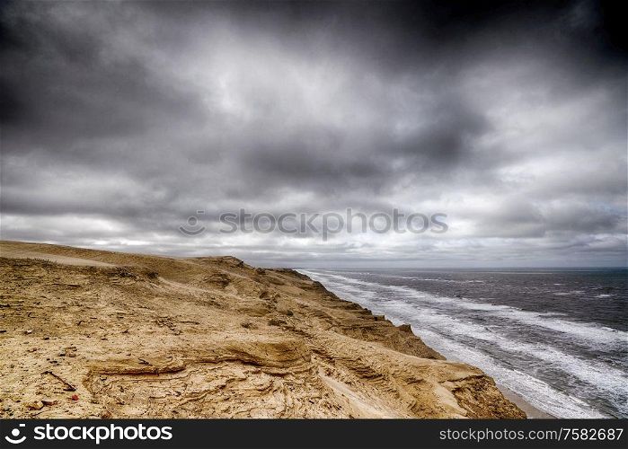 Cloudy weather over a rough coastline by the sea with dark skies
