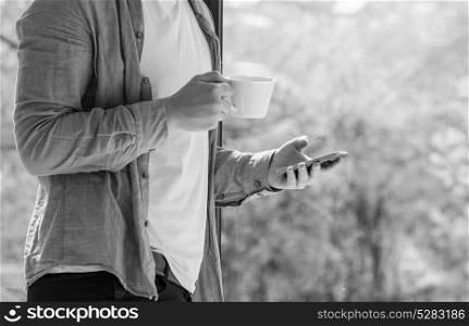 Clouseup of young man using mobile and drinking coffe