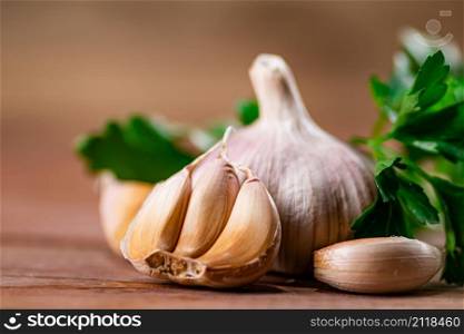 Cloves of fresh garlic with parsley. On a wooden background. High quality photo. Cloves of fresh garlic with parsley.