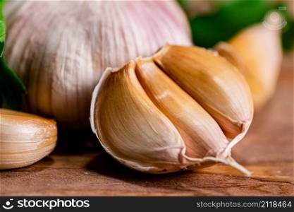 Cloves of fresh garlic with parsley. On a wooden background. High quality photo. Cloves of fresh garlic with parsley.