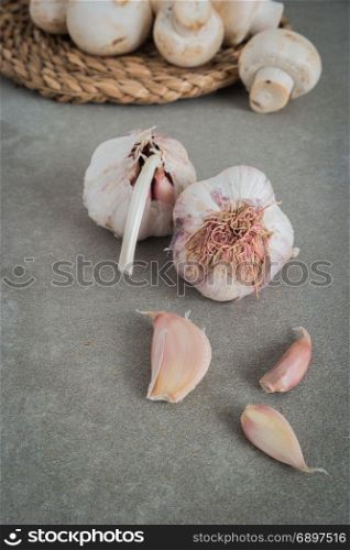 Cloves of garlic and mushrooms on a wooden black table. Vintage background. Farmer. Medicine and healthy. Traditional medicine.
