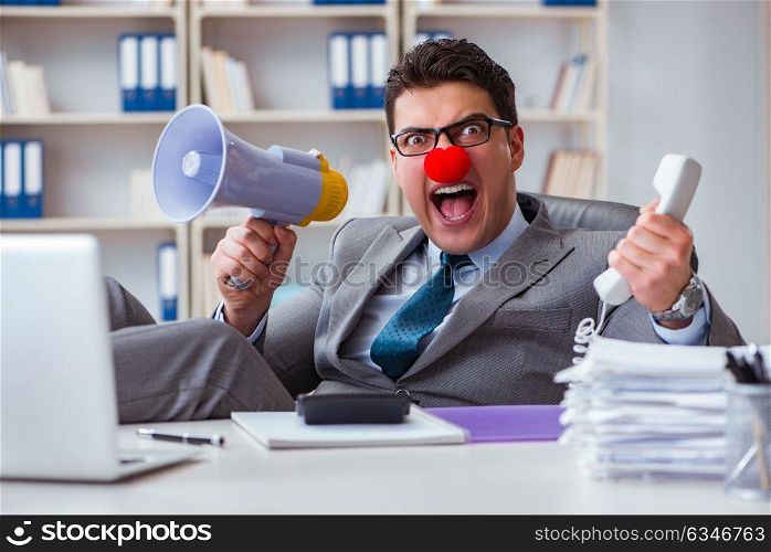 Clown businessman angry in the office with a megaphone