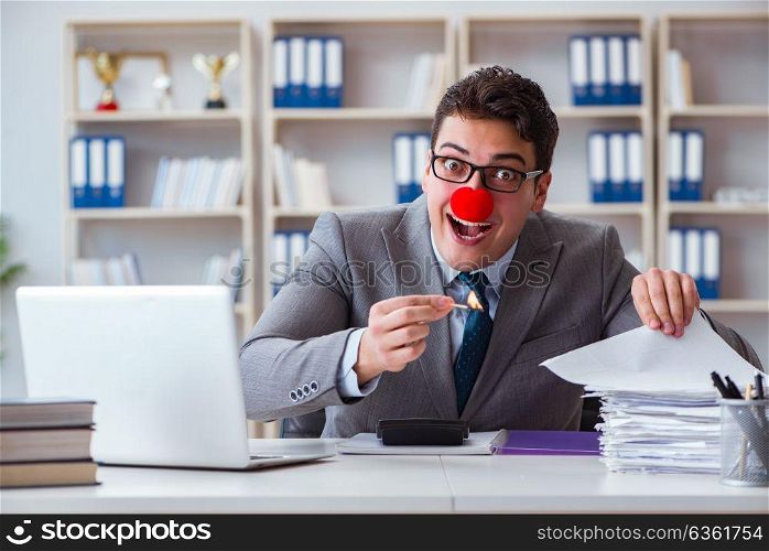 Clown businessman burning paper papers in the office
