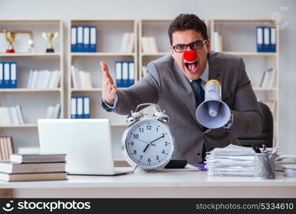 Clown businessman in the office angry frustrated with megaphone . Clown businessman in the office angry frustrated with megaphone and alarm clock