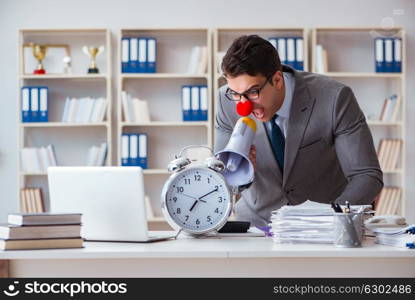 Clown businessman in the office angry frustrated with megaphone . Clown businessman in the office angry frustrated with megaphone and alarm clock